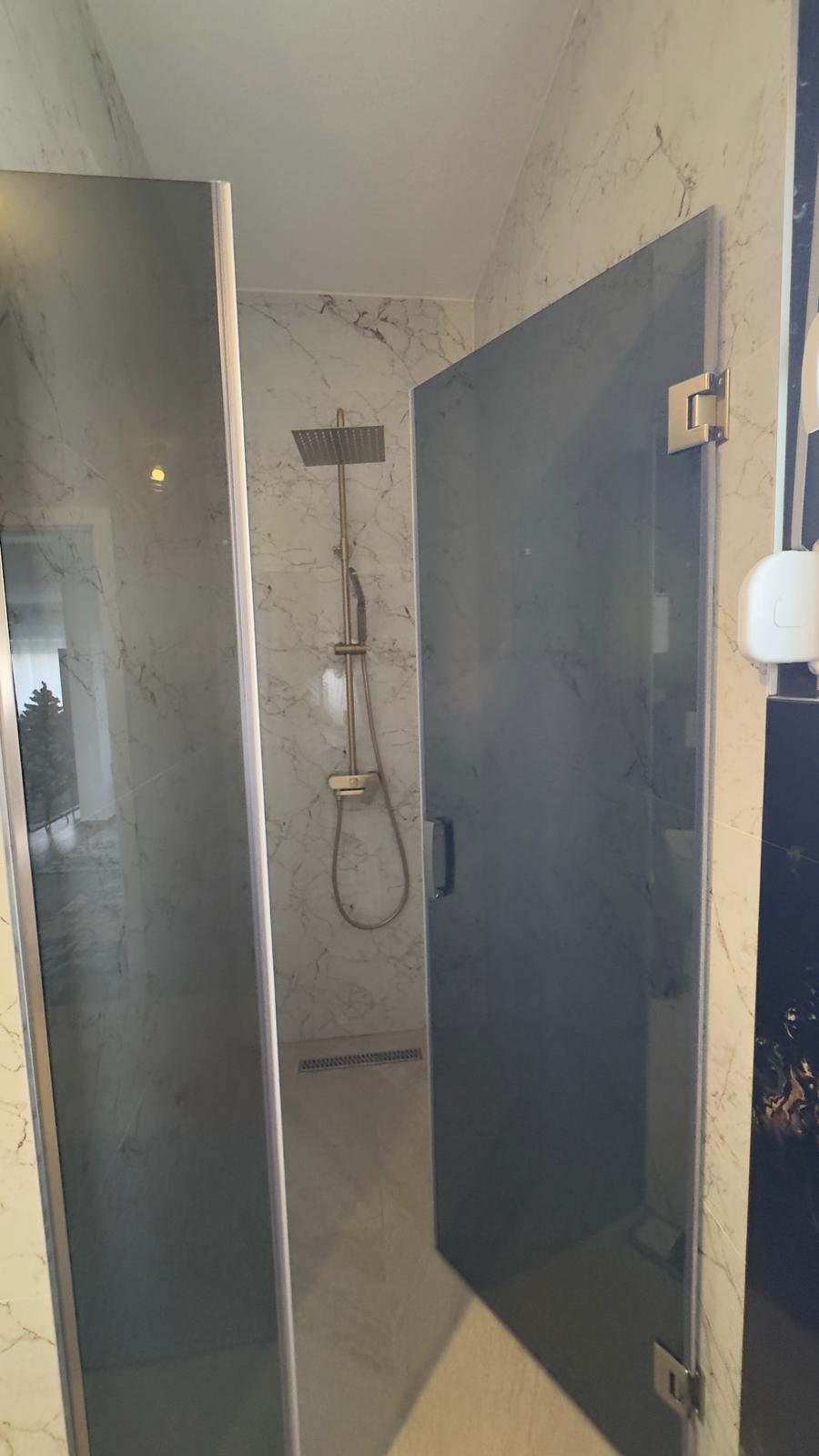 Elegant modern shower featuring marble-patterned walls, glass door, premium fixtures&mdash;an Ulcinj investment via immorenta.me by ekosphere doo.