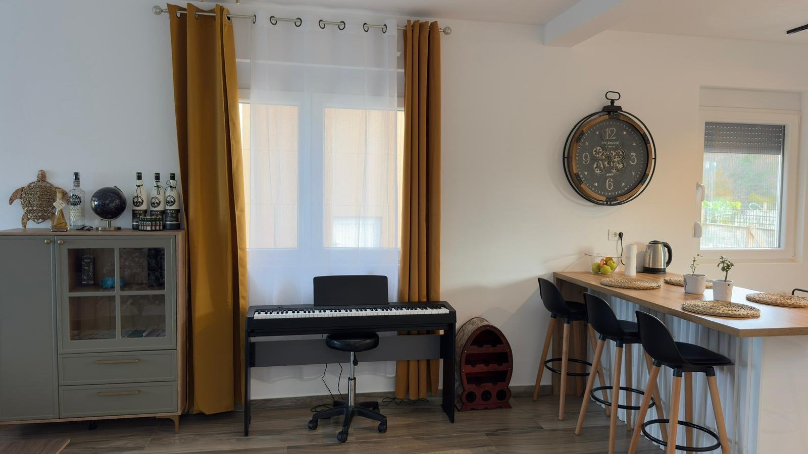 Stylish Ulcinj apartment: modern kitchen, bar stools, bright mustard curtains, ideal investment. Listed by immorenta.me/Ekosphere DOO.