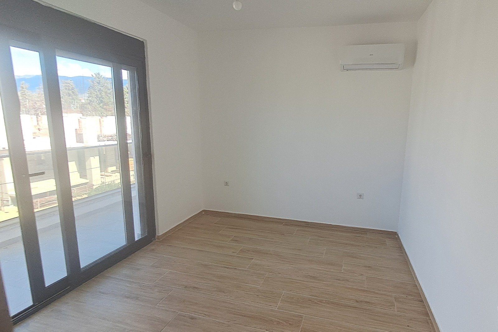 Bright, modern Ulcinj apartment: spacious room, premium wood flooring, large balcony doors, AC unit. Invest via immorenta.me (ekosphere doo).