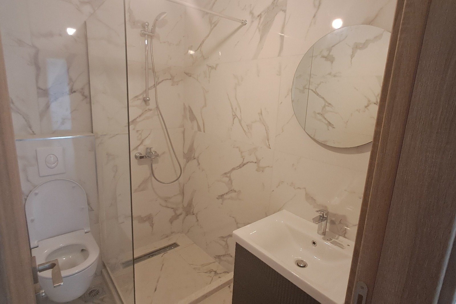 Modern bathroom in Ulcinj with marble-patterned walls, walk-in shower, and premium finishes&mdash;exclusive Montenegro-listings.me by ekosphere doo.