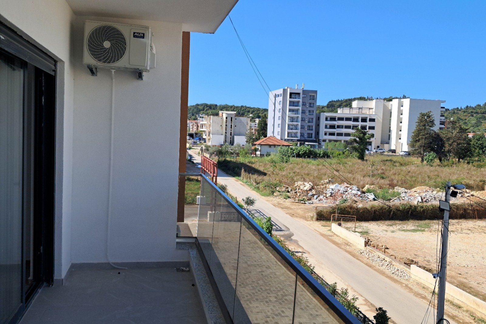 Modern balcony view with glass railing, air conditioning, and cityscape&mdash;prime Ulcinj investment on immorenta.me by ekosphere doo.