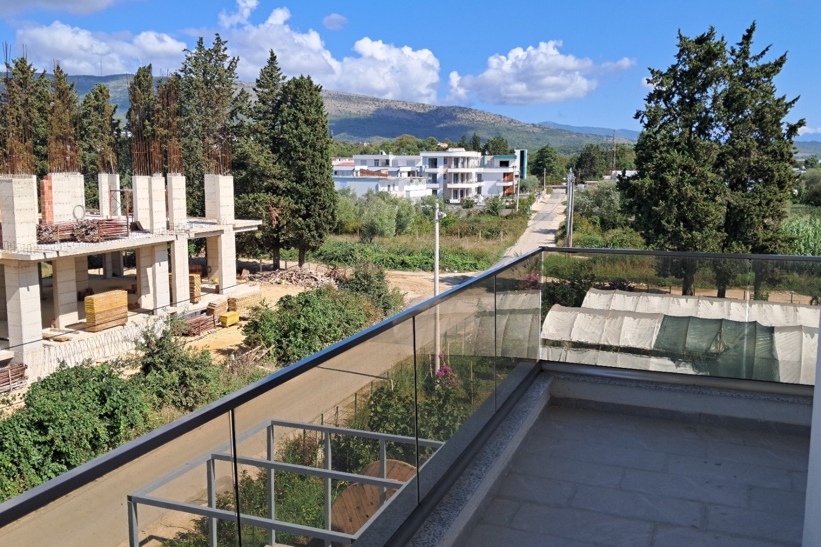 Stunning Ulcinj investment view: modern homes, lush greenery, mountain backdrop. Exclusive at immorenta.me by ekosphere doo.