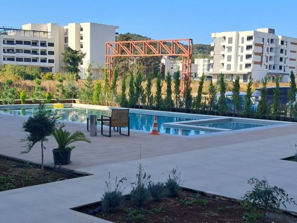 Luxuri&ouml;ser Poolbereich in Ulcinj mit Liegest&uuml;hlen, &uuml;ppigem Gr&uuml;n und modernen Apartments - exklusive Inserate auf immorenta.me von Ekosphere DOO.