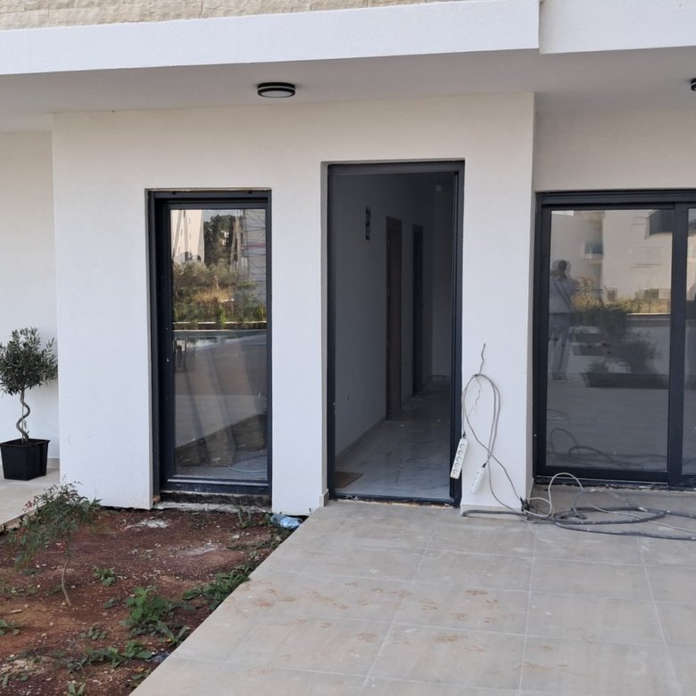 Modern Ulcinj property: sleek white-walled building with glass door, large window, open entry. Exclusive on immorenta.me by ekosphere doo.