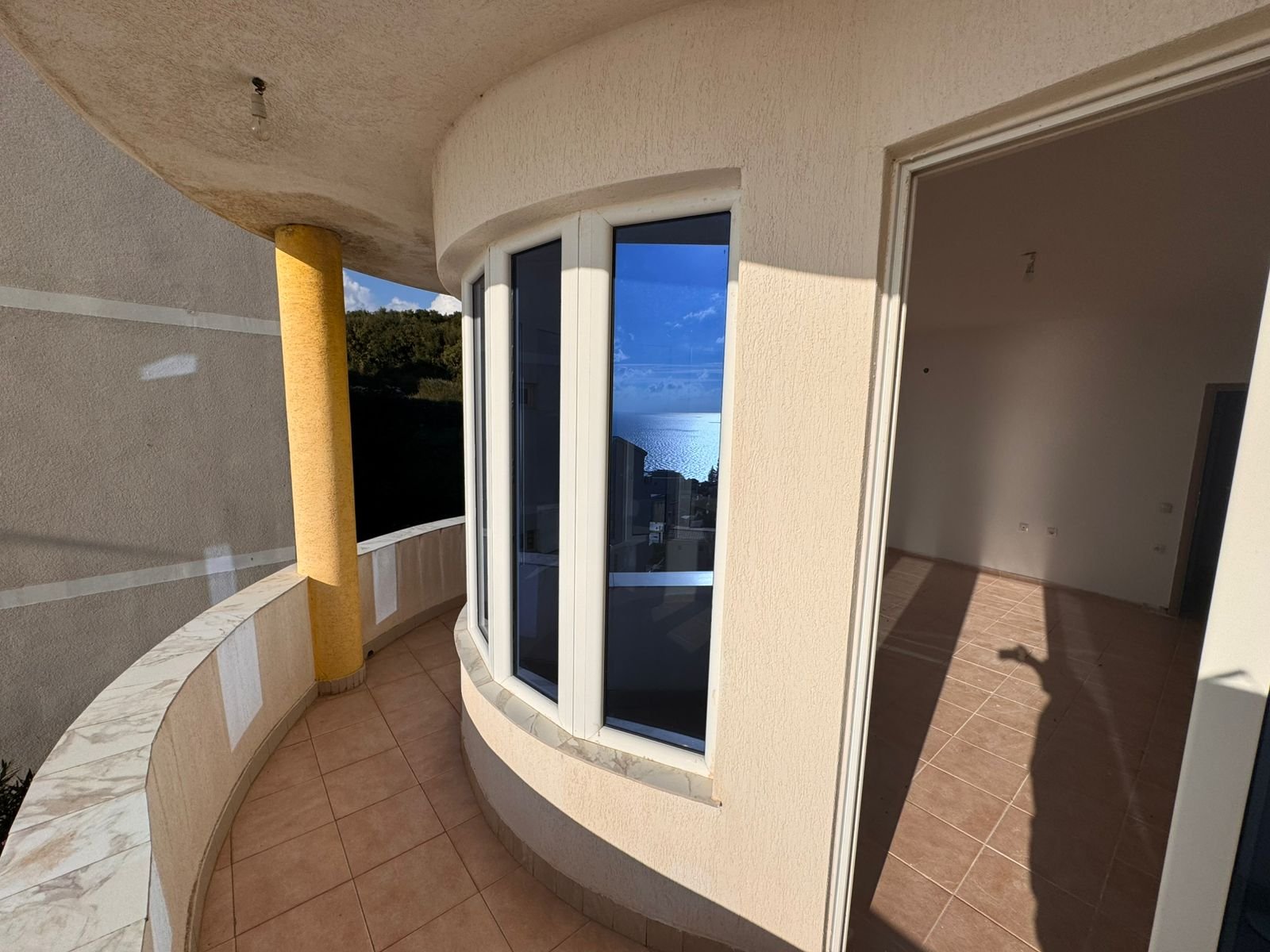 Spacious curved balcony with sea view, tiled floors, bay windows. Prime Ulcinj property via immorenta.me by ekosphere doo.
