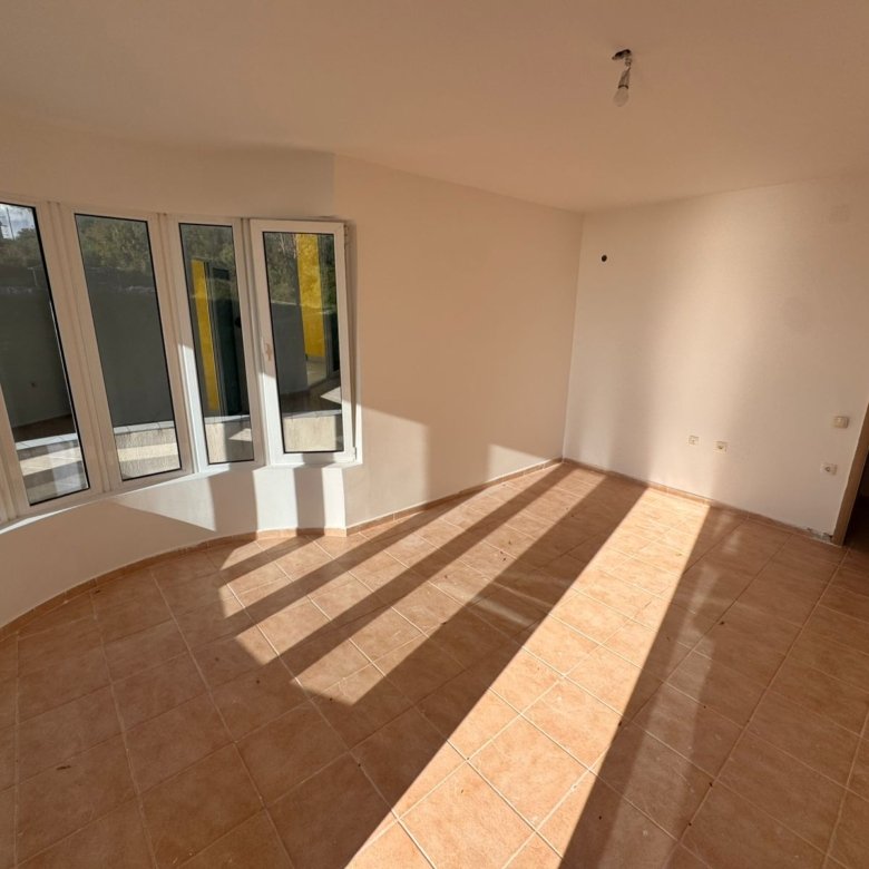 Bright, unfurnished Ulcinj property with tiled floors, curved panoramic windows, and cream walls. Featured on immorenta.me.