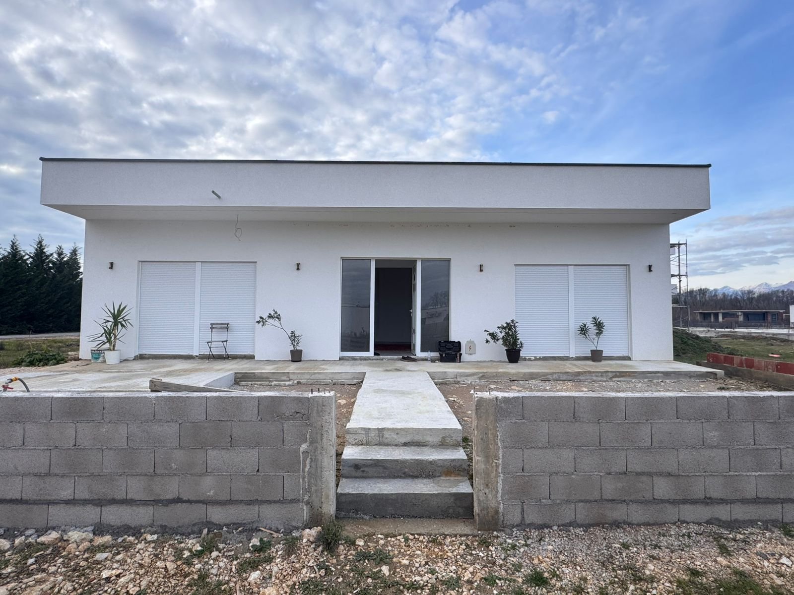 Contemporary white single-story home in Ulcinj with flat roof, shuttered sliding doors, yard space&mdash;ideal Montenegro real estate investment.