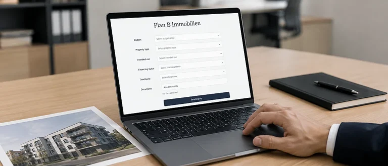 Laptop mit Immobilienformular und Unterlagen auf einem Schreibtisch.