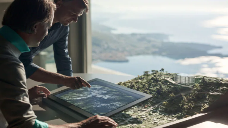Zwei Personen betrachten eine digitale Karte auf einem Tablet.